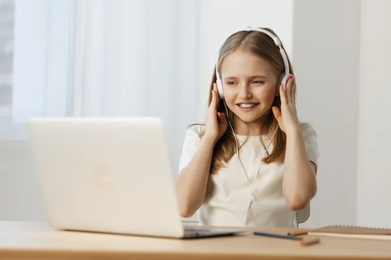 Happy girl with headphones enjoying music while working on a laptop in a bright, minimalist room A scene reflecting joy, technology, and focus