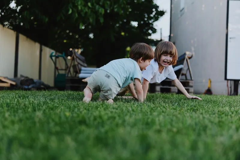 Happy children playing on the grass in the backyard. The joyful atmosphere captures their laughter and innocence.