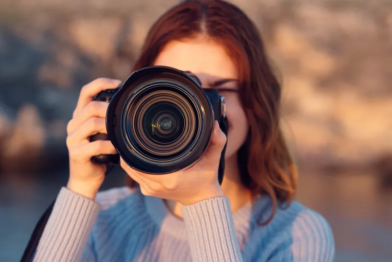 Женщина с профессиональным фотоаппаратом на открытом воздухе в горах, вид спереди