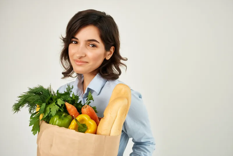 Симпатичная женщина с пакетом продуктов, овощами и доставкой из супермаркета, крупный план