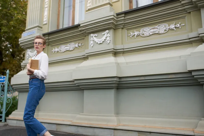 Короткостриженая женщина стоит на улице возле здания