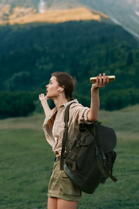 Young woman with backpack hiking outdoors in nature, holding a map and enjoying freedom. Concept of adventure, travel, lifestyle, and exploration in a mountainous area.