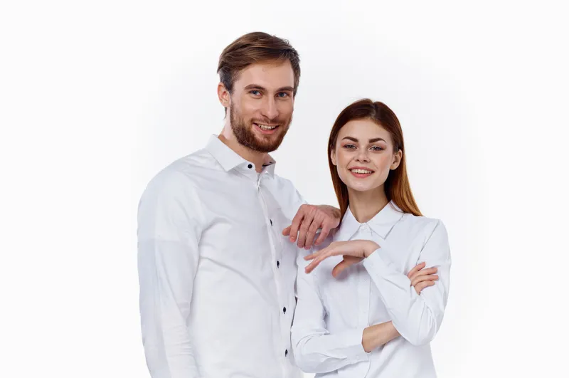 Мужчина и женщина в белых рубашках стоят рядом друг с другом, улыбаются
