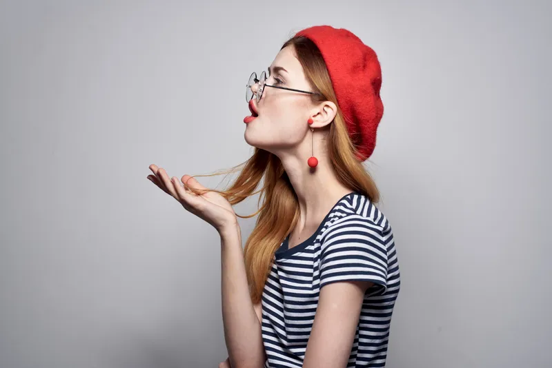 Француженка в красной шляпе позирует, демонстрируя макияж и моду