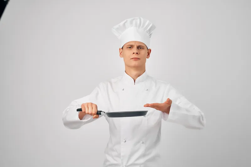 Повар с кухонной утварью, сковородой, работа по приготовлению пищи