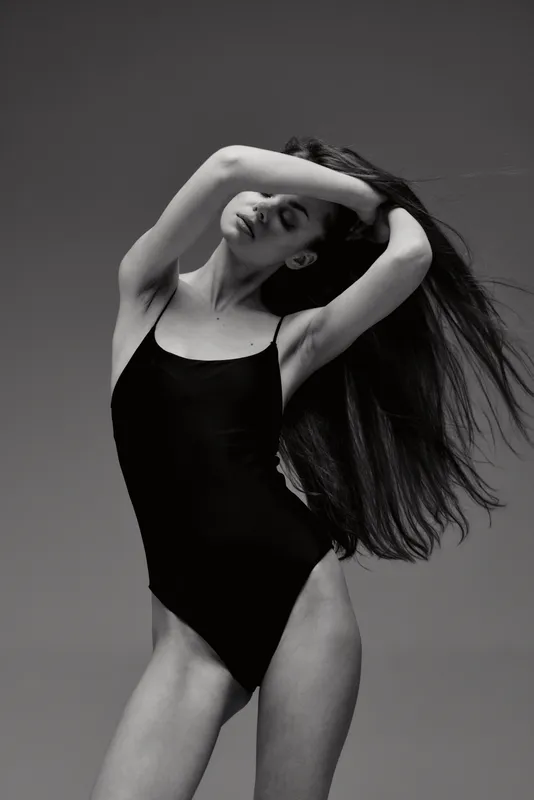 graceful woman posing in black bodysuit with flowing hair in black and white elegance