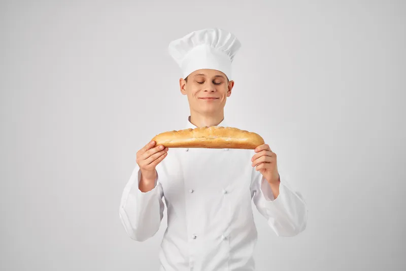Повар-мужчина держит в руках багет, свежий продукт, профессиональная работа