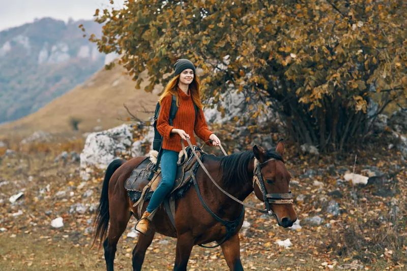 Женщина-туристка верхом на лошади в горах