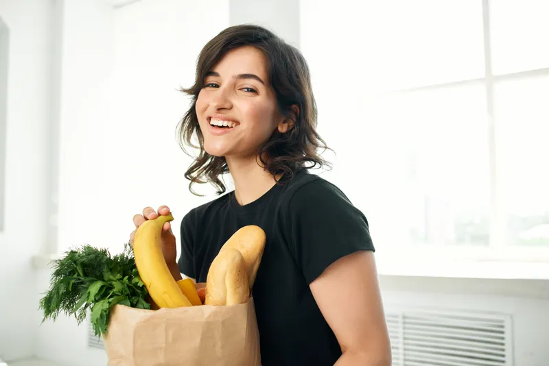 Весёлая брюнетка с сумкой для продуктов, доставка здоровой пищи, овощи