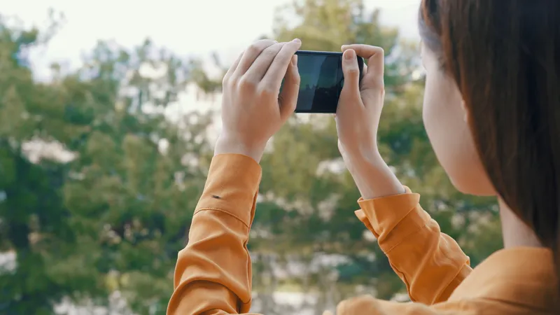Женщина на открытом воздухе с телефоном в руках фотографирует панораму природы