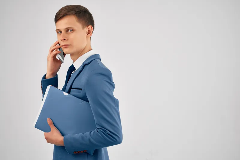 Деловой мужчина с синей папкой разговаривает по телефону