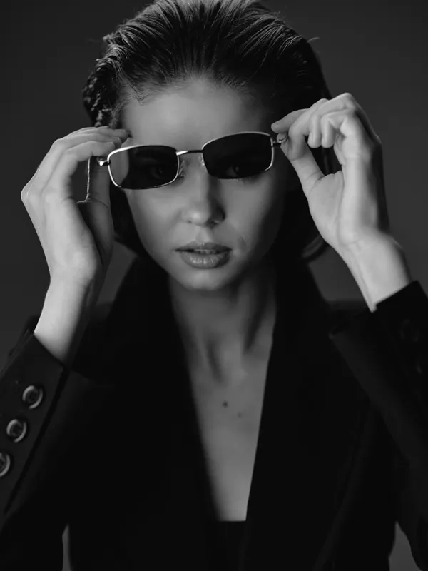 Black and white portrait of a fashionable woman wearing sunglasses with a confident expression and stylish black blazer