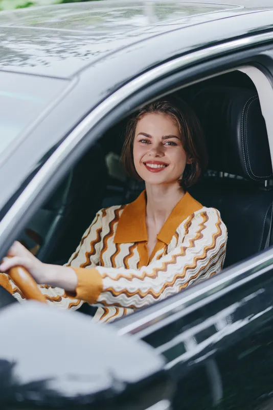 Car, driver, woman, smile a cheerful woman sits in the driver's seat behind the wheel with a warm smile, ready for a journey, enjoying confidence and comfort inside a stylish modern vehicle