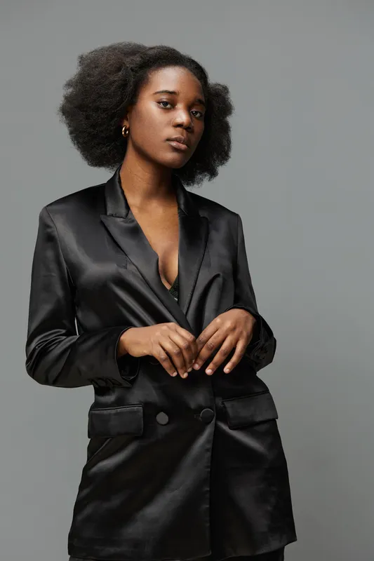 Elegant Black Woman in Satin Blazer Showcasing Confidence and Style Against a Neutral Background