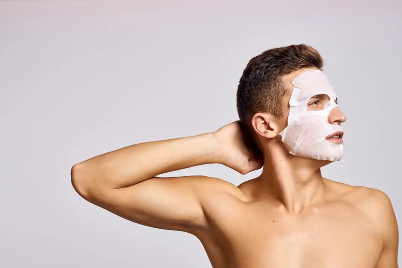 Мужчина с очищающей маской на лице на фоне чёрных точек