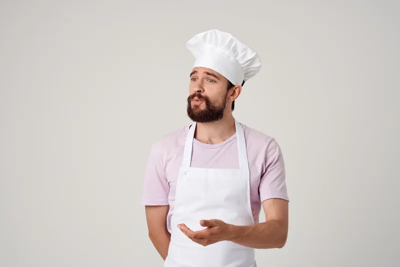 Шеф-повар в белом фартуке работает на профессиональной кухне ресторана