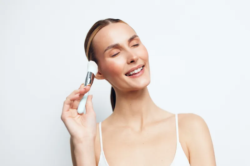 Woman skincare face serum beauty hygiene spa self care routine, smiling young woman in closeup holds serum dropper near cheek, white background clean hydration