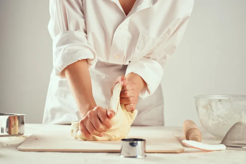 На кухне раскатывают тесто, используя муку и продукты для приготовления выпечки