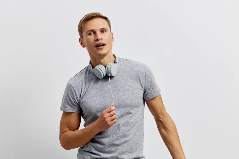 Young man slim fit gray t-shirt wear headphones hold wire look aside isolated white background casual style digital detox concept