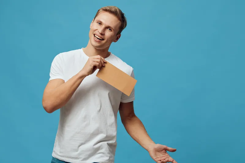 smiling young caucasian man white t-shirt holding envelope communication concept isolated blue background modern lifestyle