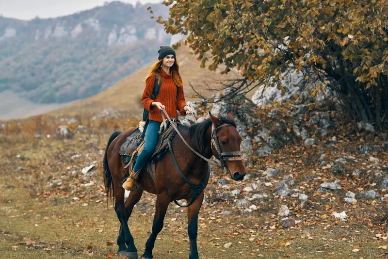 Женщина-туристка верхом на лошади в горах