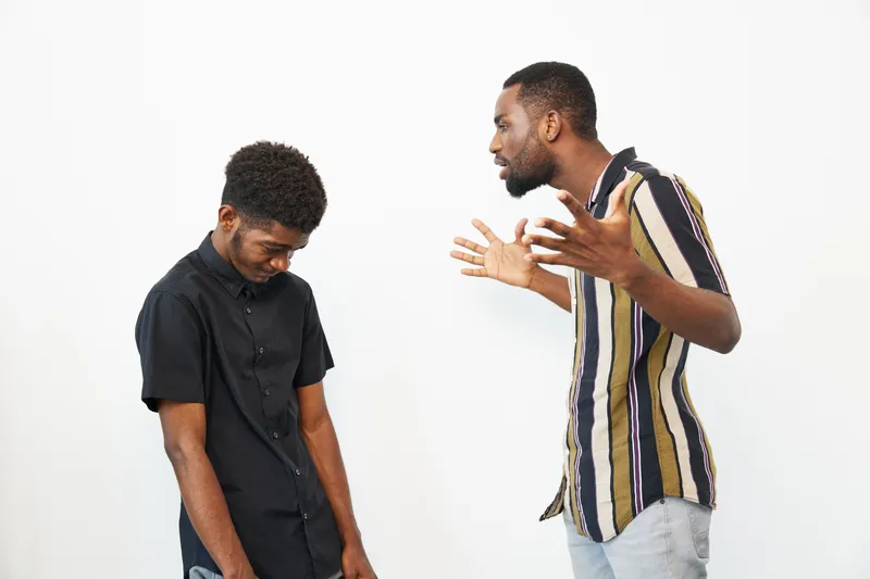 Group of black men expressing emotions while engaged in a serious conversation, showcasing body language and intensity.