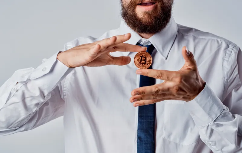 Биткоин-монета в руках бизнесмена, который управляет криптовалютой