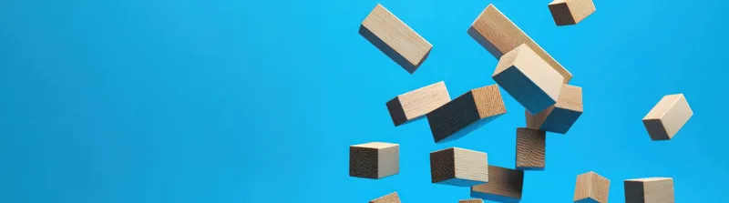 Динамичная композиция из деревянных кубиков, парящих на ярко-голубом фоне, символизирующая творчество, игривость и образовательные темы