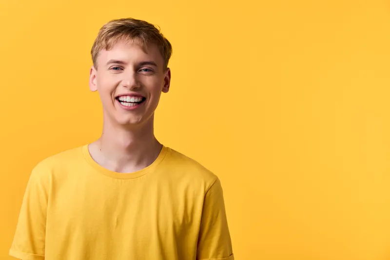 Smiling male model in a yellow tee against a vivid yellow background, radiating energy, positivity and approachability for lifestyle, advertising and branding visuals