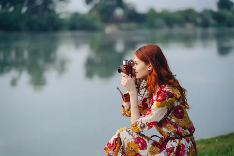 Женщина в разноцветном платье с фотоаппаратом в руках на улице