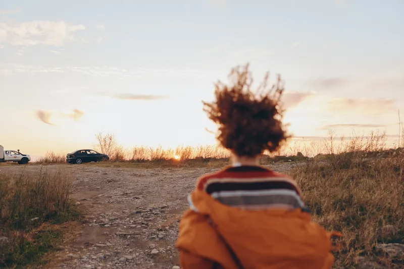 Sunset, child, countryside, road, outdoors, golden, hour, back, view, lifestyle, rear view of a child in orange jacket walking on a dirt road, warm backlit sky, calm travel mood
