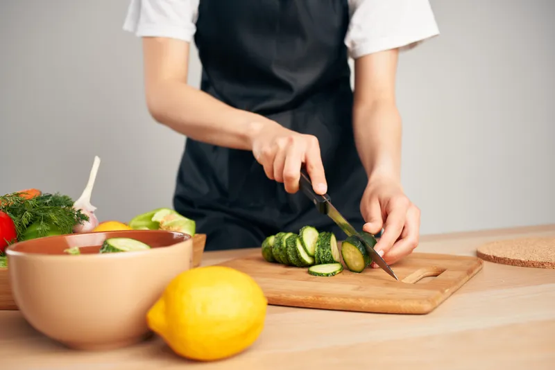 Нарезка продуктов для ингредиентов салата из свежих овощей во время приготовления