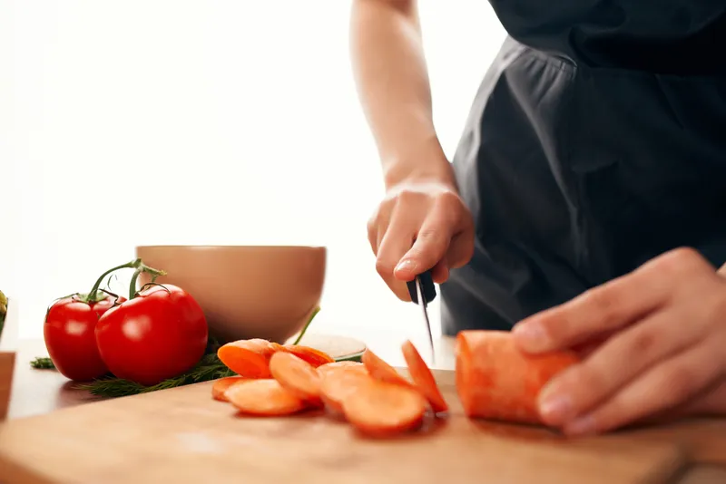 Нарезка моркови на разделочной доске ножом, кухня, приготовление пищи