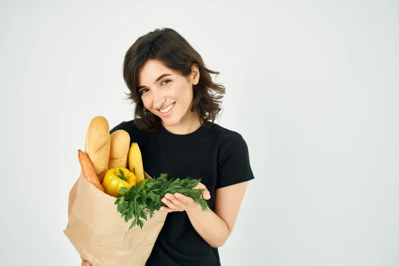 Весёлая брюнетка с пакетом продуктов здорового питания из супермаркета K-supermarket