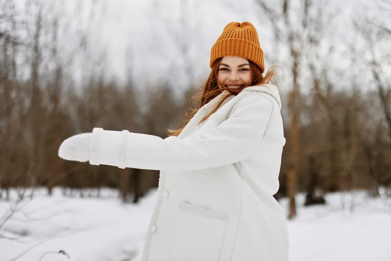 Счастливая молодая женщина в зимней одежде и шапке