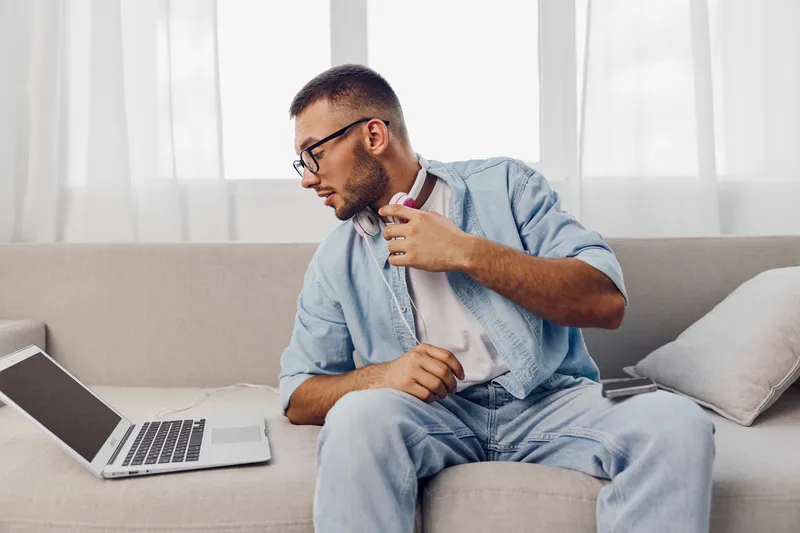 Thoughtful man taking a digital detox at home, reflecting on AI anxiety and work-life blur, captured in a cozy, soft masculinity setting.