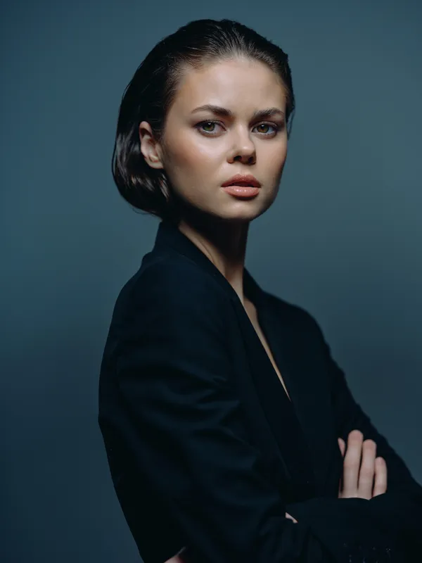 serious woman portrait in dark suit with crossed arms against gray background