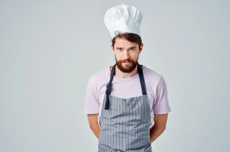 Мужчина в фартуке профессионально работает на кухне, обслуживая гостей