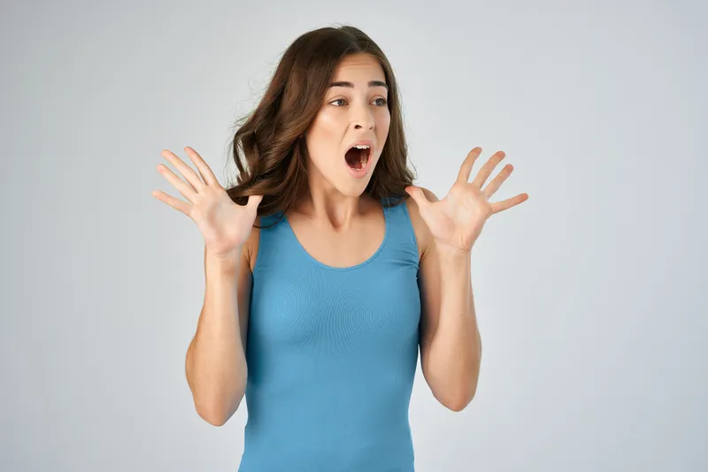 Женщина держится за волосы, демонстрируя прическу и моду в студийной обстановке, передавая эмоции