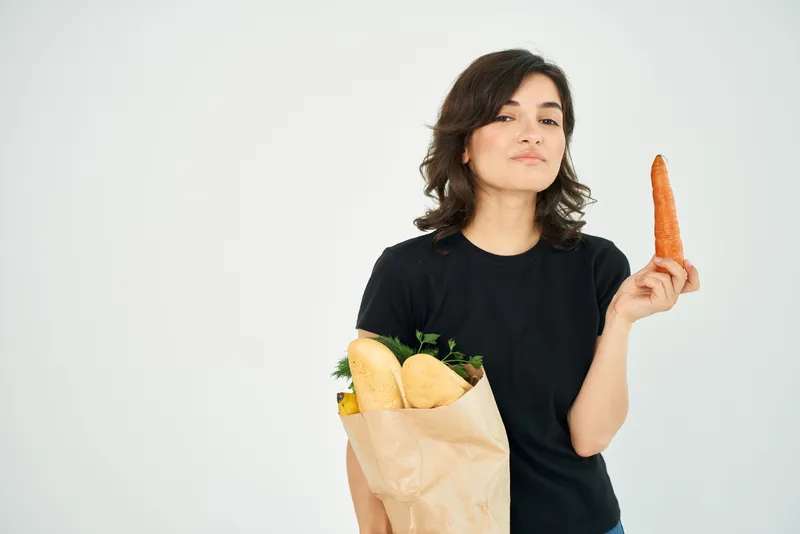 Женщина в чёрной футболке с пакетом продуктов, доставка здоровой еды, светлый фон