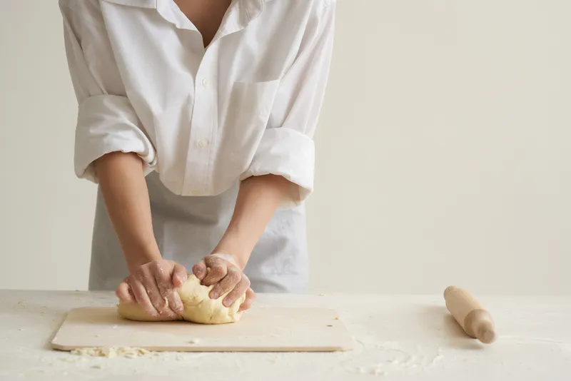 На кухне раскатывают тесто, используя муку и продукты из муки