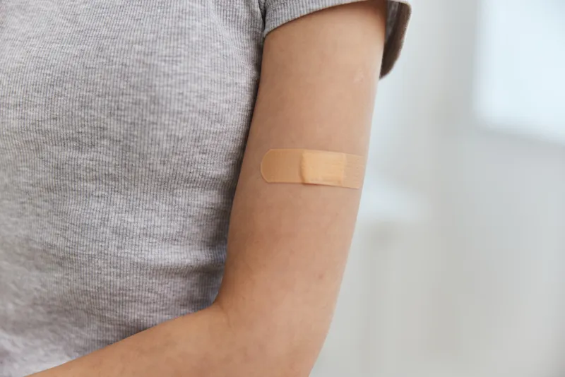 Лейкопластырь на плече женской руки, иммунизация, вакцинация, здоровье, безопасность