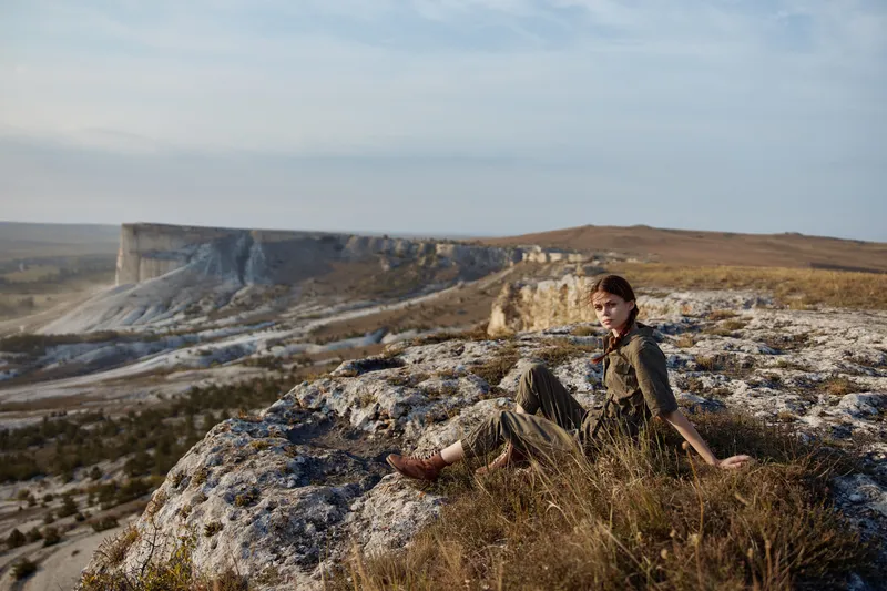 Женщина созерцает величественный горный вид с края утёса во время своего путешествия