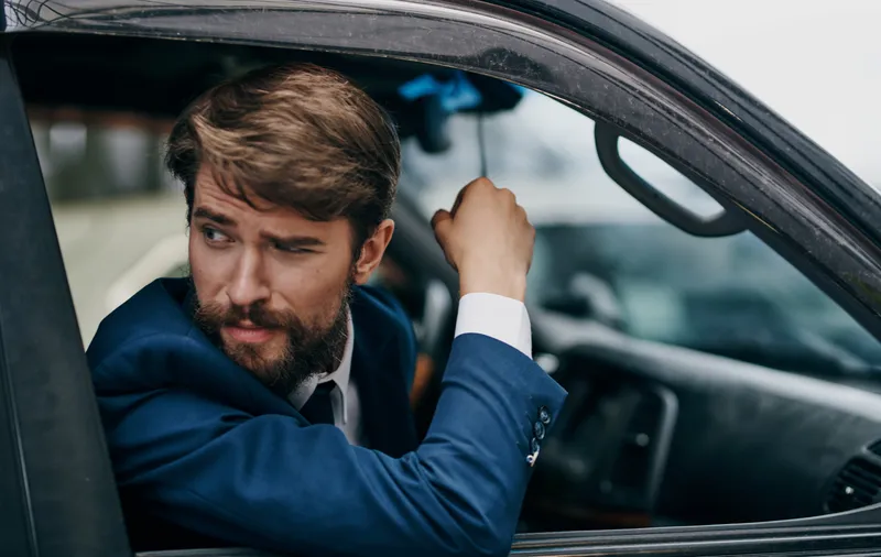 Мужчина в костюме выглядывает из окна автомобиля, веселая поездка, образ жизни