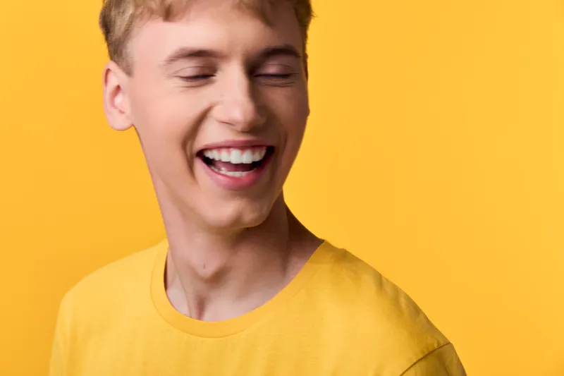 Smiling man in a bright yellow tee against a vibrant backdrop, capturing a moment of pure joy and energy, casual style, informal vibe, upbeat mood, and carefree happiness for lifestyle, fashion, or