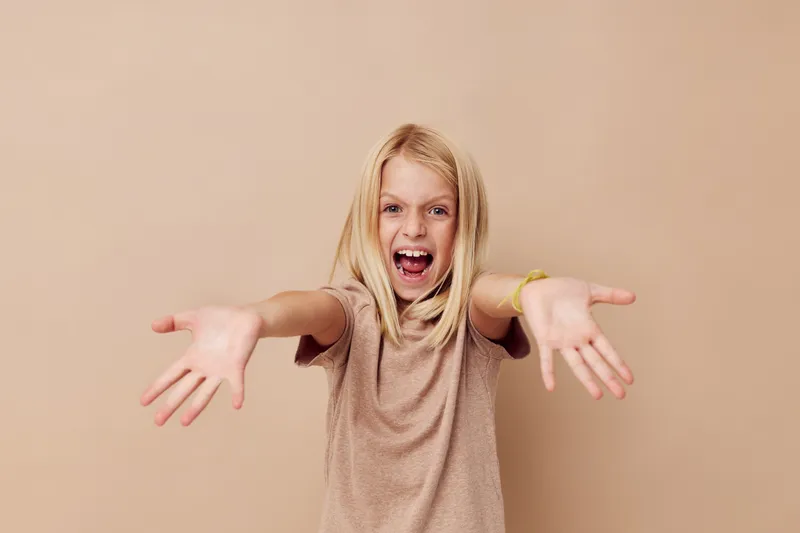 Счастливая милая девушка в бежевой футболке на изолированном фоне
