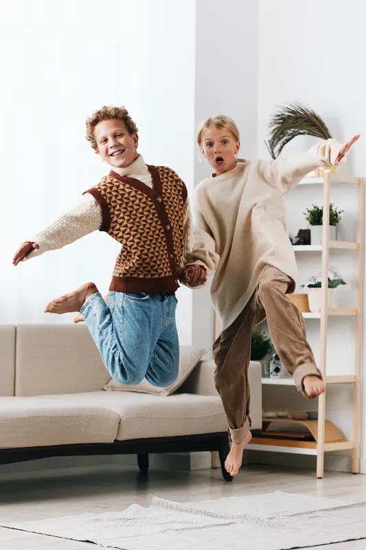 Authentic play scene featuring children indoors, celebrating school life through playful movement and candid laughter, capturing a lively lifestyle moment.