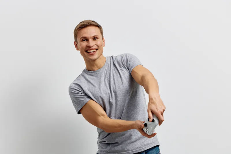 smiling young caucasian man wearing gray t-shirt play video game hold controller enjoy leisure time isolated on white background digital detox concept