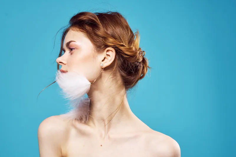 Привлекательная женщина, пушистые серьги, косметика, мода на синем фоне