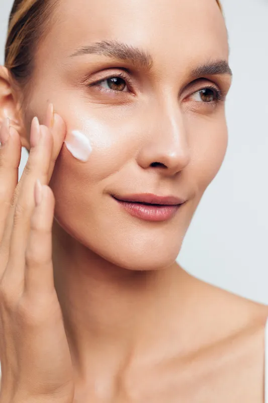 Woman applying face cream in closeup, skincare and beauty routine, spa wellness concept, soft studio lighting, calm cosmetic treatment for smooth skin